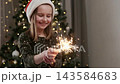 Happy Little Girl enjoys sparklers in front of Christmas tree at home during the holiday season 143584683