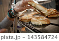 Girl Wearing Gloves And Picking Up Fresh Bread Rolls From A Shelf In The Supermarket Bakery 143584724