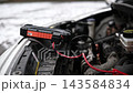 Connecting A Portable Jump Starter Battery Device To An Engine With A Low Battery To Start In Winter In Cold Temperatures 143584834