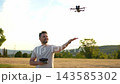 Asian woman flying a drone in a sunny park on a beautiful afternoon 143585302