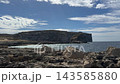 Rocky coast of Gozo island in Malta with limestone cliffs overlooking the Mediterranean sea under a blue sky with clouds. Coastal scenery, island travel, natural landscape, seaside tourism, clear sea. 143585880