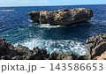 Fungus Rock at Dwejra Bay on Gozo island in Malta rises from the blue Mediterranean sea as waves break along limestone cliffs. Rocky coastline, natural landmark, island travel, coastal scenery of Gozo 143586653