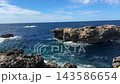 Fungus Rock at Dwejra Bay on Gozo island in Malta rises from the blue Mediterranean sea as waves break along limestone cliffs. Rocky coastline, natural landmark, island travel, coastal scenery of Gozo 143586654
