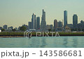 A helicopter flies near the Chicago skyline above the Lake Michigan waterfront on a sunny summer day. Modern skyscrapers and calm water create a dramatic urban cityscape scene. 143586681