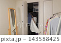 クローゼットから持ってきたシャツを鏡の前で選ぶ女性 クローゼットから持ってきたシャツを鏡の前で選ぶ女性 143588425