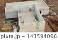 Observing the aerial perspective of a construction site with a partially finished building and surrounding materials. 143594096