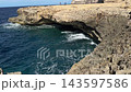 Dwejra Bay on Gozo island in Malta shows a coastal limestone cliff and sea cave above turquoise Mediterranean waves. Rocky shoreline, natural erosion, island sightseeing, scenic coastal landscape view 143597586