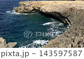 Dwejra Bay on Gozo island in Malta shows a coastal limestone cliff and sea cave above turquoise Mediterranean waves. Rocky shoreline, natural erosion, island sightseeing, scenic coastal landscape view 143597587