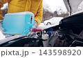 Driver Pours Blue Winter Car Window Cleaning Liquid With The Hood Open On Parking 143598920