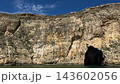 The Inland Sea tunnel at Dwejra on Gozo island, Malta, opens as a dark sea cave beneath tall limestone cliffs. Mediterranean coastline, boat excursion, natural geology, island sightseeing and scenery. 143602056