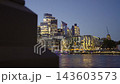 Camera sliding reveal shot framing the illuminated City of London financial district skyline and HMS Belfast during blue hour twilight 143603573