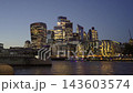 Vertical rising reveal shot rising over a wall to show the illuminated City of London skyline and HMS Belfast during blue hour twilight 143603574