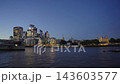 Wide static shot across the River Thames of the illuminated City of London skyline and Tower of London during blue hour twilight with HMS Belfast on the left 143603577