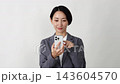 A middle-aged businesswoman using a smartphone; white background. 143604570