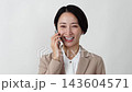 A middle-aged businesswoman making a phone call on her smartphone against a white background. 143604571