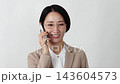 A middle-aged businesswoman making a phone call on her smartphone against a white background. 143604573
