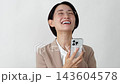 A middle-aged businesswoman makes a triumphant gesture while looking at her smartphone against a white background. 143604578