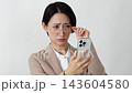 A middle-aged businesswoman with presbyopia who has difficulty seeing her smartphone screen (white background) 143604580