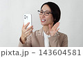 A businesswoman making a video call on her smartphone against a white background. 143604581