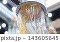 Plastic pneumatic conveying. Golden yellow plastic pellets flowing through transparent industrial tubing. Plastic manufacturing show material transport. Automated processing polymer production tech. 143605645