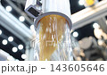 Plastic pneumatic conveying. Golden yellow plastic pellets flowing through transparent industrial tubing. Plastic manufacturing show material transport. Automated processing polymer production tech. 143605646