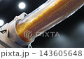 Plastic pneumatic conveying. Golden yellow plastic pellets flowing through transparent industrial tubing. Plastic manufacturing show material transport. Automated processing polymer production tech. 143605648
