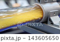 Plastic pneumatic conveying. Golden yellow plastic pellets flowing through transparent industrial tubing. Plastic manufacturing show material transport. Automated processing polymer production tech. 143605650
