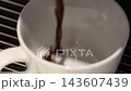 Pouring coffee slow motion footage. Close up white coffee cup. It captures pouring fresh coffee followed by hot water or milk. Create hot Americano Cappuccino or latte coffee. Fresh brew cafe concept 143607439