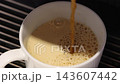 Pouring coffee slow motion footage. Close up white coffee cup. It captures pouring fresh coffee followed by hot water or milk. Create hot Americano Cappuccino or latte coffee. Fresh brew cafe concept 143607442