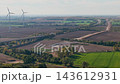 Aerial drone view highway traffic crossing a viaduct through agricultural fields beside wind turbines in Germany. Autumn landscape reveals road construction, farmland and renewable energy 143612931