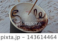 Close up of sugar being stirred with a wooden stick on top of cappuccino milk foam with chocolate text smile close up. 143614464