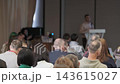 Seated attendees facing a conference speaker 143615027