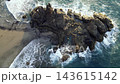 A high aerial view looks straight down on the sea stacks of Benijo as waves wrap around the black rock. A dramatic top down angle of Tenerife's wildest beach. 143615142