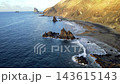 A drone view sweeps across the curve of Benijo beach with its sea stacks set against dark cliffs. Wide island scenery for travel and destination marketing on Tenerife. 143615143