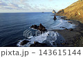 An aerial view opens over Benijo beach with its black sand curve and famous sea stacks lit by late sun. A signature establishing shot of Tenerife's wildest coastline. 143615144