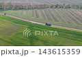Aerial drone view shows tanker truck driving along rural road between green agricultural fields in Germany. Scenic autumn countryside reveals farmland, cultivated soil, trees and transport logistics 143615359