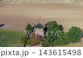 Aerial drone footage shows old stone windmill with damaged wooden sails surrounded by trees and harvested farmland in rural Germany. Autumn countryside highlights traditional heritage and agriculture 143615498