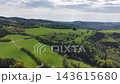 Wide aerial panorama shows green pastures, winding trails, and forested ridges stretching toward distant hills. Soft overcast light creates serene, expansive countryside scenery. 143615680
