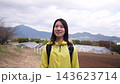 A circle-shot portrait of a smiling woman against a backdrop of fields and mountains in a hilly area. 143623714