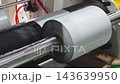 Process of rolling grey material on a machine in a manufacturing setting 143639950