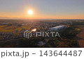 夕日に染まる埼玉県熊谷市の大型物流倉庫と田園風景のドローン空撮 143644487