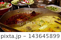 A close-up of noodles bubbling in a boiling, spicy hot pot broth. 143645899