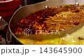 A close-up of noodles bubbling in a boiling, spicy hot pot broth. 143645900