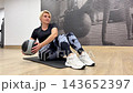 A person exercises with a medicine ball on a mat while focusing on core strength at the gym during afternoon hours 143652397