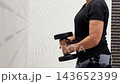 Woman lifting dumbbells in a home gym setting, showcasing strength training with a focus on arm exercises and fitness progression 143652399