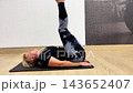 A person performs challenging yoga poses in a studio with wood flooring. Various positions are shown, including stretches and balances 143652407