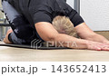 A person performs a stretching exercise on a mat in a gym. The focus is on proper technique and body posture 143652413