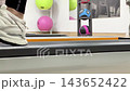 People walk and jog on a treadmill in a gym setting with various exercise equipment and fitness balls around them as they stay active 143652422