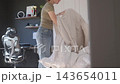 Woman takes duvet cover off comforter while changing bed linen at home. Bedroom cleaning, laundry preparation and everyday household routine 143654011