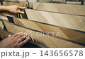 Showcasing a range of beautiful laminate and parquet materials, hands gently examine different styles and textures, perfect for enhancing any living space with elegance and warmth. 143656578